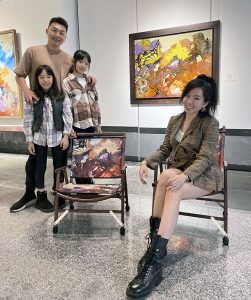 莊明中的作品被開發文創商品椅子，王先生一家特地將椅子拿來展場與原作《蝶舞》合影